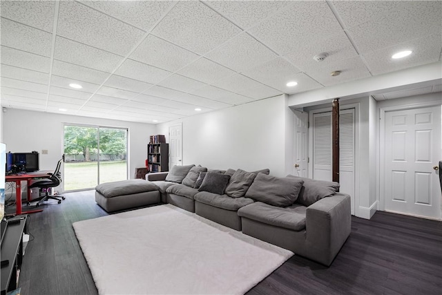 living room featuring a drop ceiling and dark hardwood / wood-style floors