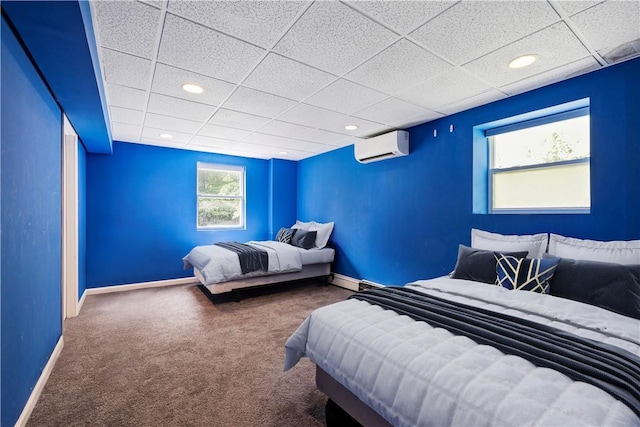 bedroom featuring carpet, a drop ceiling, and an AC wall unit