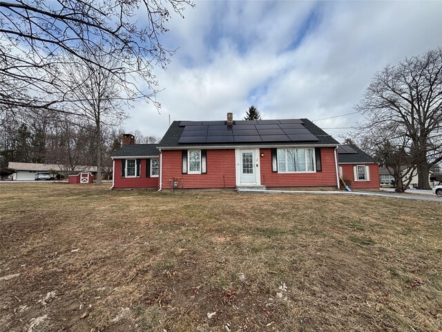 view of front of property featuring solar panels and a front lawn