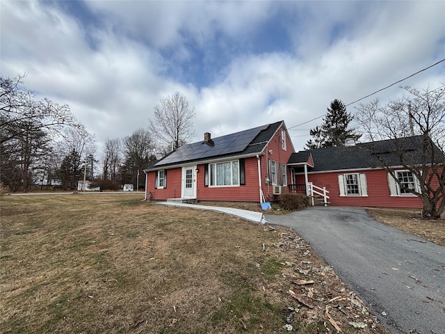 view of front of house featuring solar panels and a front lawn