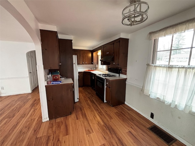 kitchen featuring range with gas cooktop, white fridge, light hardwood / wood-style floors, tasteful backsplash, and dark brown cabinetry