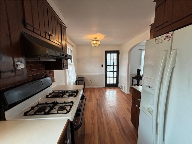 kitchen with white appliances, light wood-type flooring, and dark brown cabinets