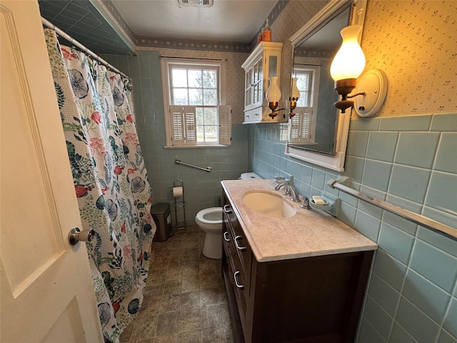 bathroom with toilet, vanity, and tile walls