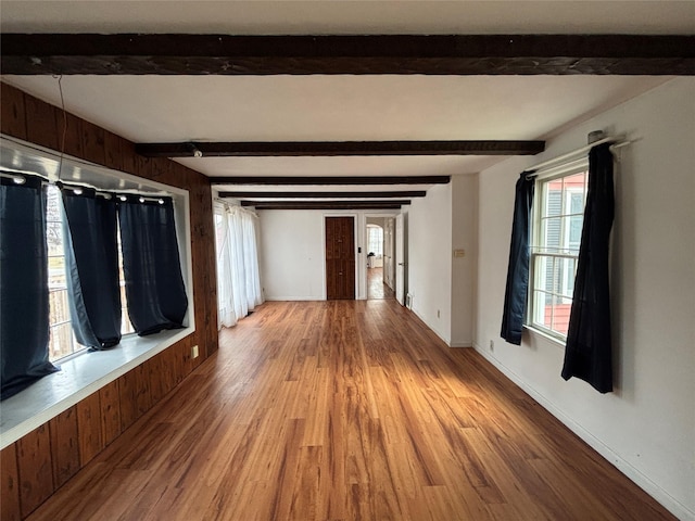 unfurnished room featuring hardwood / wood-style floors and beam ceiling