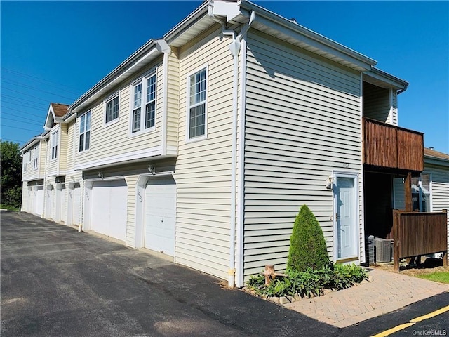 view of property exterior featuring a balcony, a garage, and central air condition unit