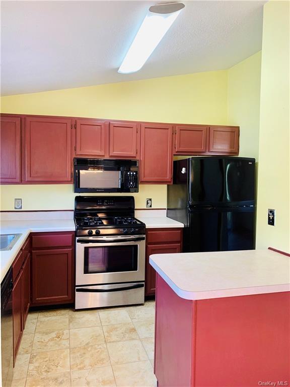 kitchen featuring black appliances, sink, and vaulted ceiling