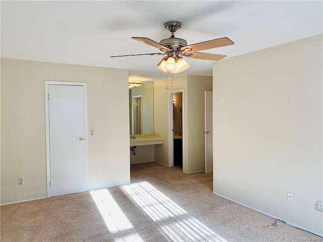 unfurnished bedroom featuring connected bathroom, light colored carpet, and ceiling fan