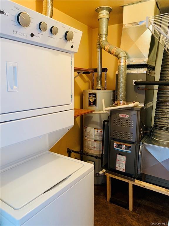 utilities featuring stacked washer / dryer and water heater