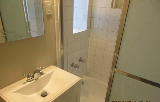 bathroom featuring combined bath / shower with glass door and sink