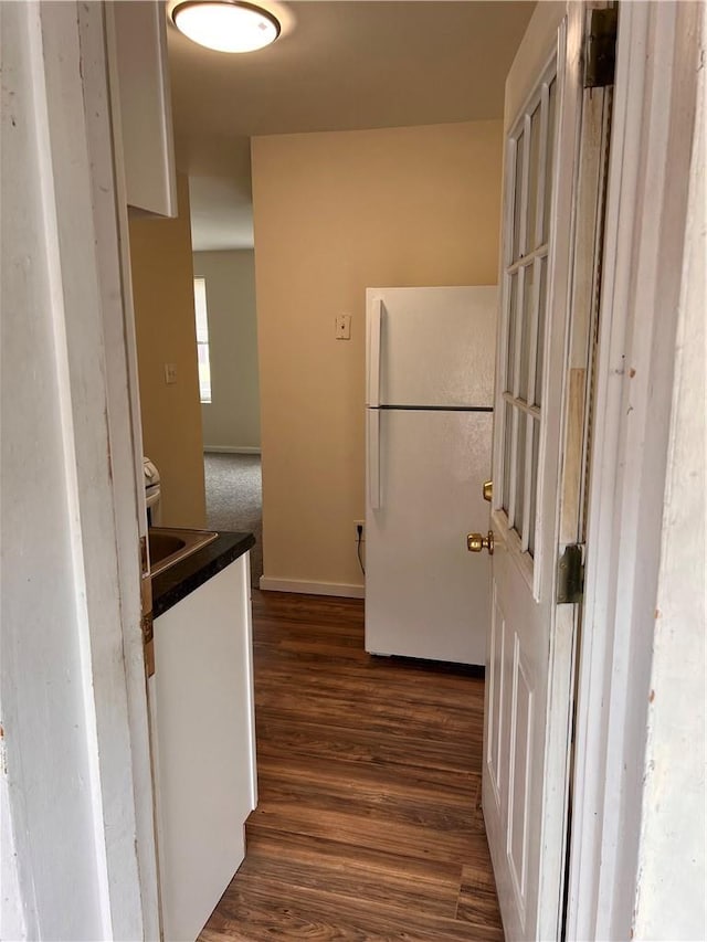 kitchen with dark hardwood / wood-style flooring, white fridge, and white cabinetry