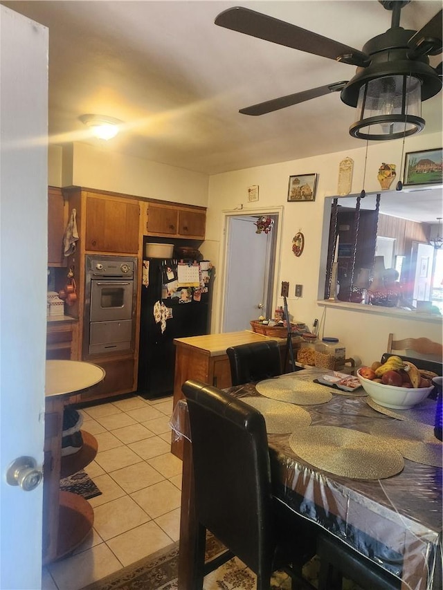 kitchen featuring black fridge, light tile patterned floors, oven, and ceiling fan