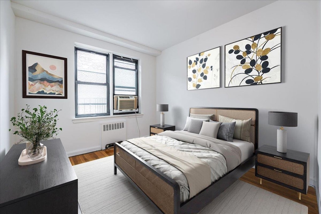 bedroom with cooling unit, hardwood / wood-style floors, and radiator heating unit