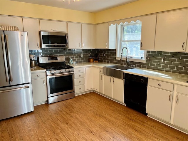 kitchen featuring white cabinetry, light wood-type flooring, sink, and appliances with stainless steel finishes