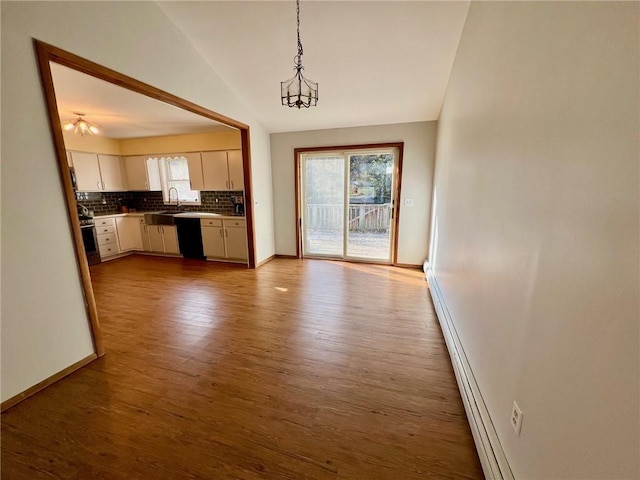 kitchen featuring pendant lighting, white cabinets, vaulted ceiling, decorative backsplash, and light hardwood / wood-style floors