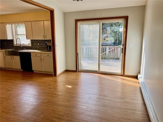 kitchen featuring decorative backsplash, black dishwasher, baseboard heating, and light hardwood / wood-style flooring