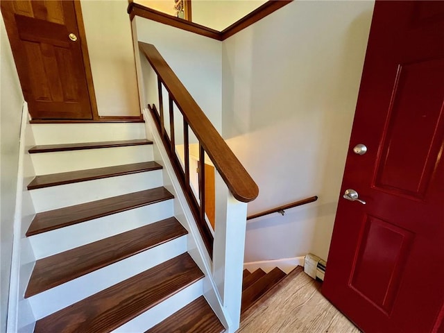 stairs featuring hardwood / wood-style floors and a baseboard radiator