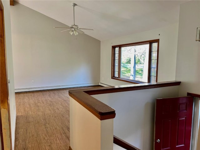 interior space featuring a baseboard heating unit, light hardwood / wood-style floors, and lofted ceiling