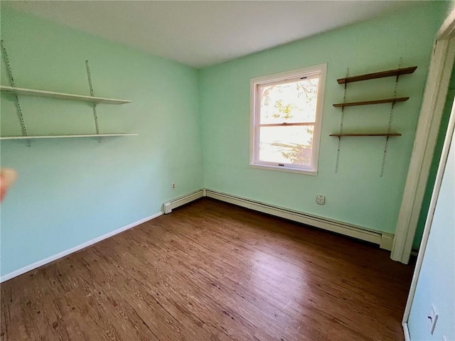 empty room featuring wood-type flooring and baseboard heating