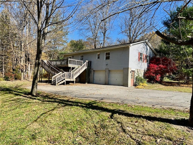 rear view of house featuring a garage, a deck, and a yard