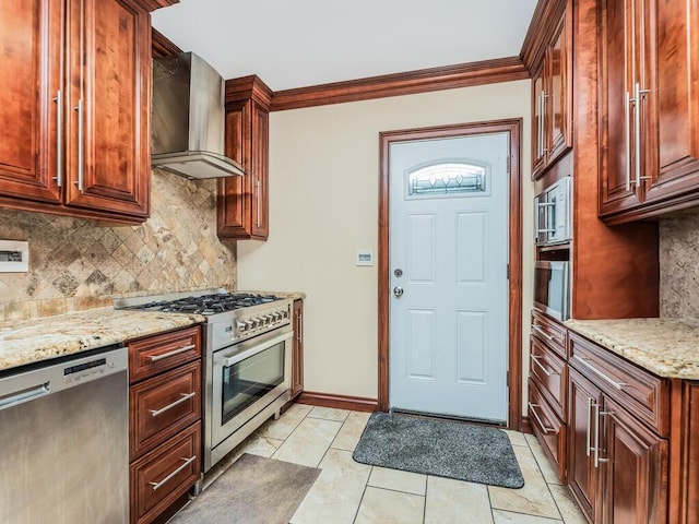 kitchen featuring light stone counters, wall chimney range hood, backsplash, and appliances with stainless steel finishes