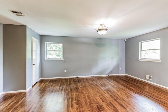 spare room featuring a healthy amount of sunlight and dark hardwood / wood-style flooring