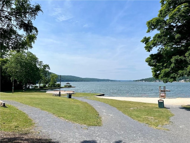 surrounding community with a water view and a lawn