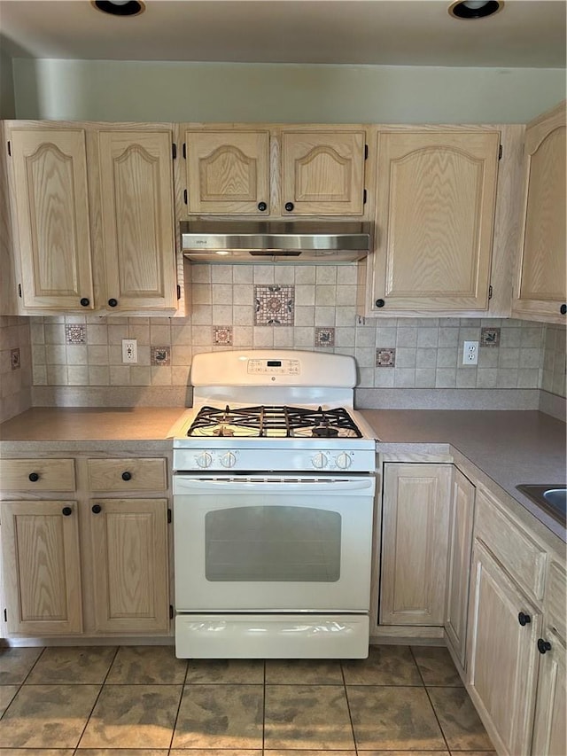 kitchen with decorative backsplash, light brown cabinets, white gas range oven, and tile patterned flooring