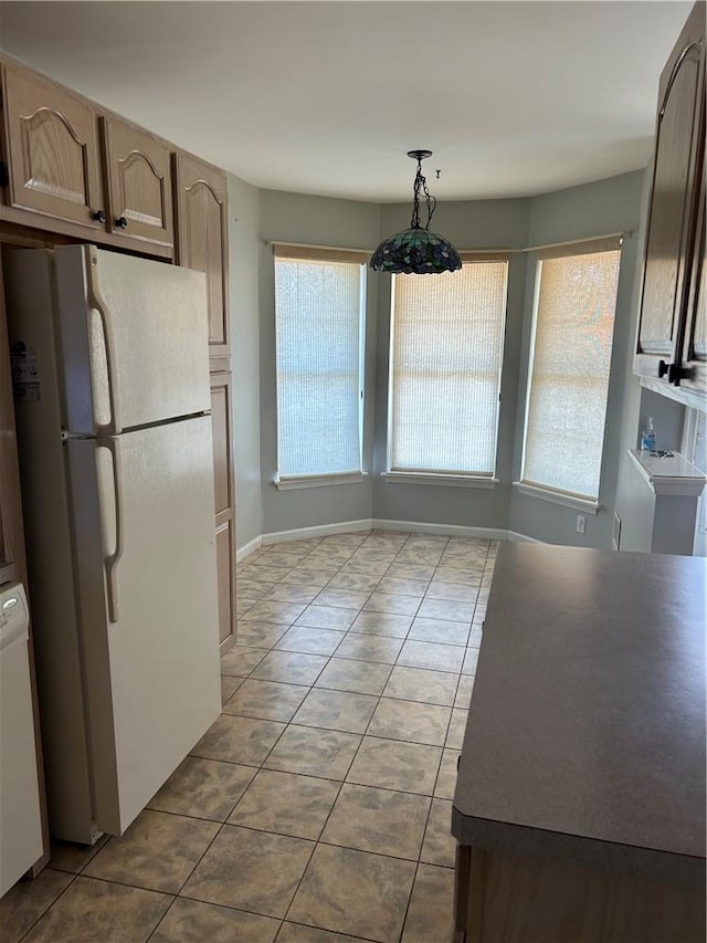 kitchen featuring tile patterned flooring, white fridge, hanging light fixtures, and light brown cabinetry