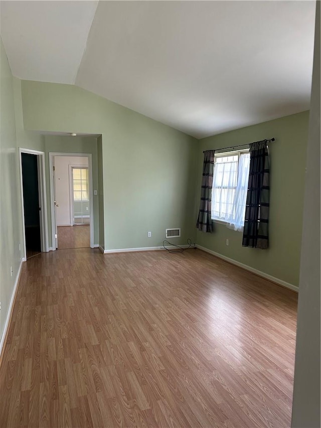 unfurnished room featuring light hardwood / wood-style floors and vaulted ceiling