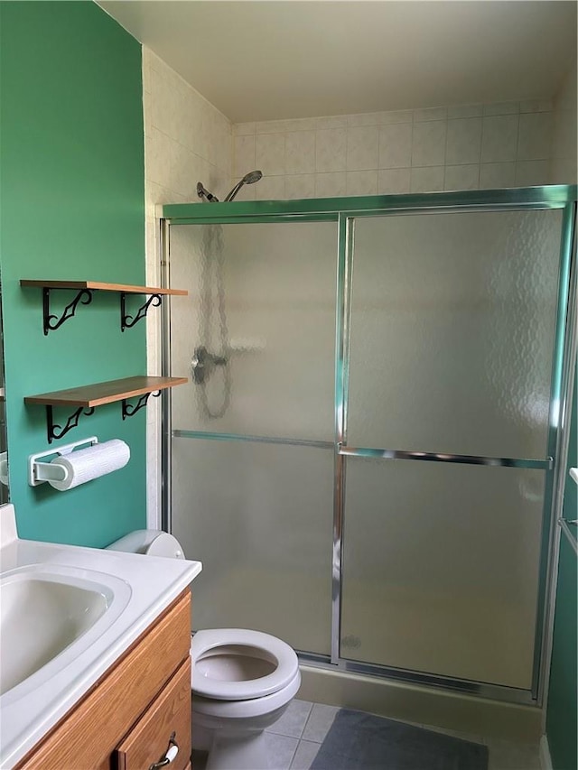 bathroom with tile patterned floors, vanity, toilet, and a shower with door