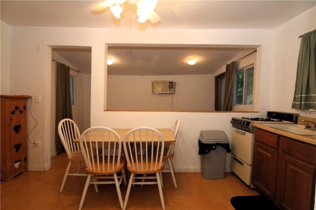 dining room featuring a wall mounted air conditioner, ceiling fan, light wood-type flooring, and sink