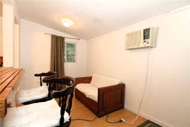 living area featuring vaulted ceiling, a wall unit AC, and light hardwood / wood-style flooring