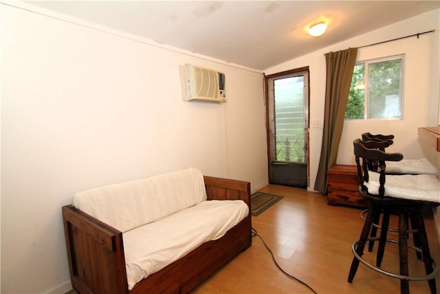 sitting room featuring light hardwood / wood-style flooring, a wall mounted air conditioner, and vaulted ceiling