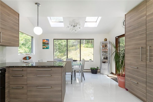 kitchen featuring dark stone countertops, vaulted ceiling with skylight, hanging light fixtures, and an inviting chandelier