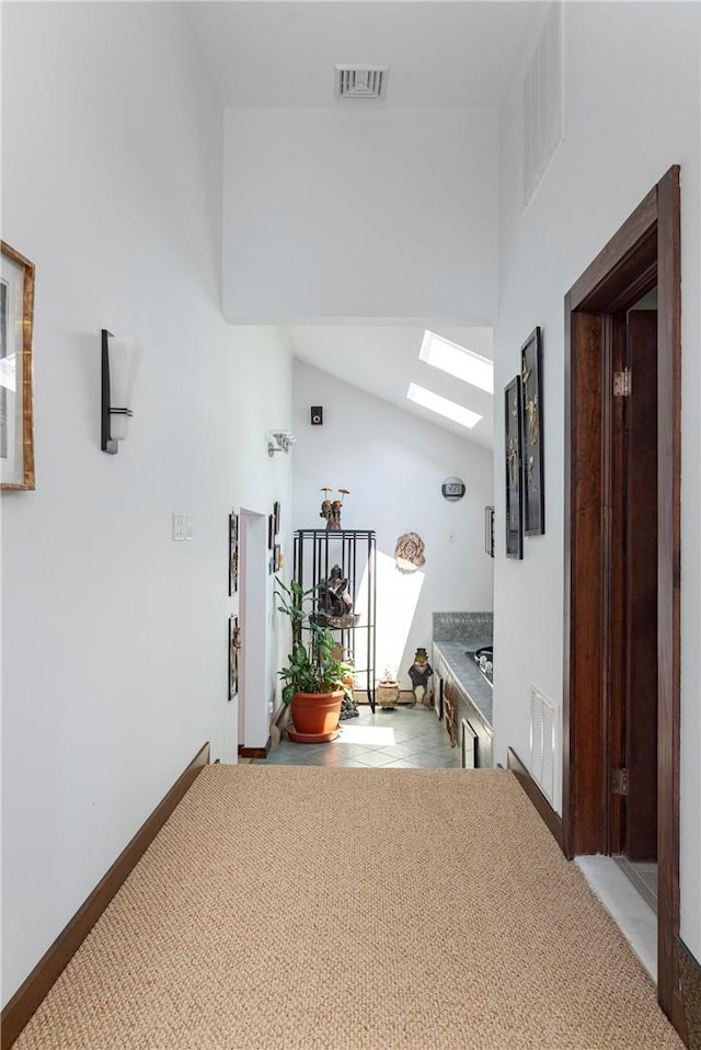 hall featuring carpet flooring and lofted ceiling with skylight