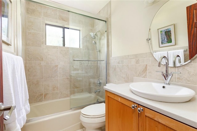 full bathroom with vanity, toilet, tile walls, and bath / shower combo with glass door