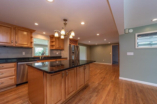 kitchen featuring sink, hanging light fixtures, stainless steel appliances, a kitchen island, and light wood-type flooring