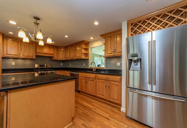 kitchen with sink, light hardwood / wood-style flooring, appliances with stainless steel finishes, decorative light fixtures, and a chandelier