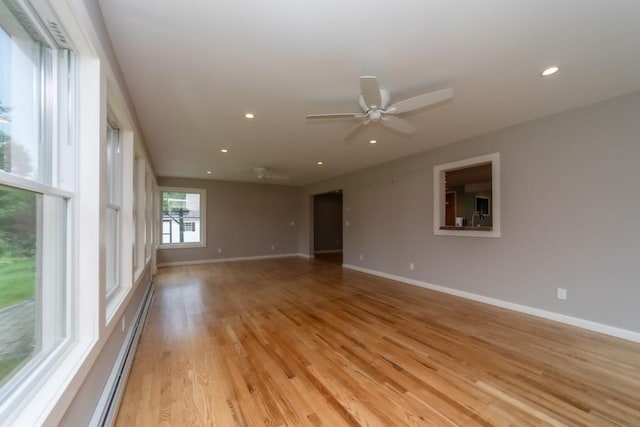 empty room featuring ceiling fan, baseboard heating, and light hardwood / wood-style flooring