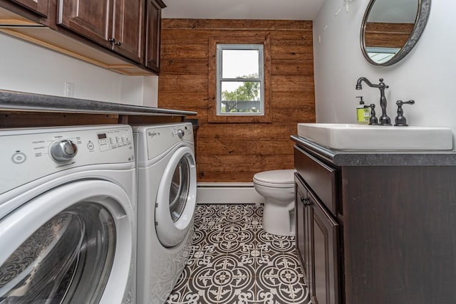 laundry room featuring washer and clothes dryer, sink, wooden walls, and tile patterned floors