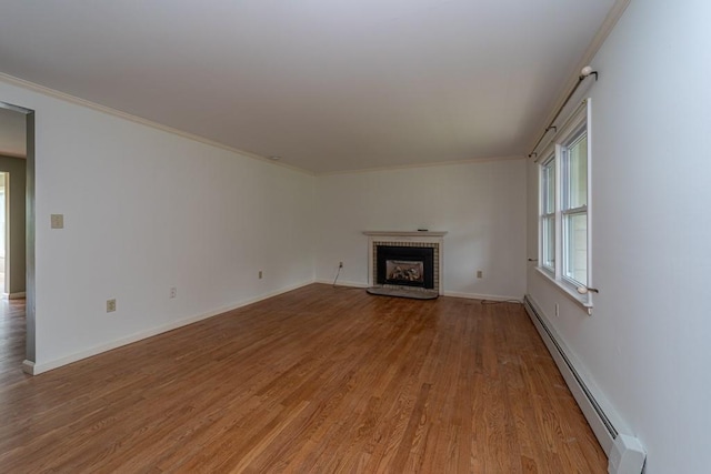 unfurnished living room with crown molding, light hardwood / wood-style flooring, and a baseboard heating unit