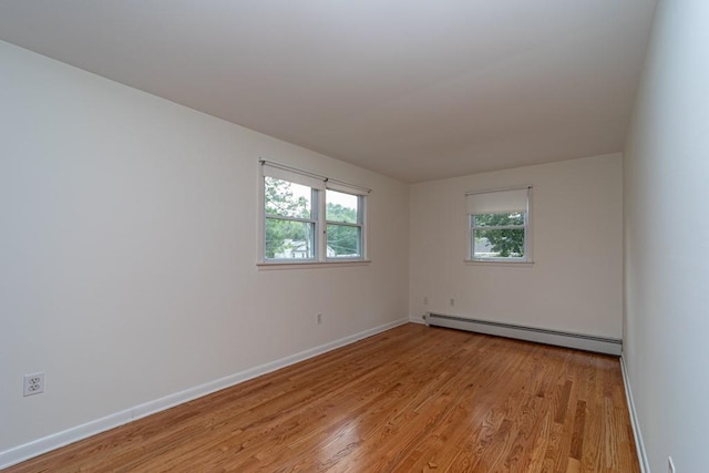 empty room with baseboard heating, a wealth of natural light, and light hardwood / wood-style floors