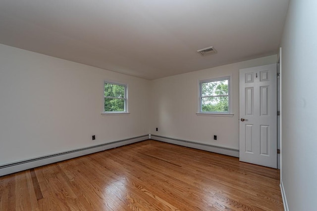 unfurnished room featuring baseboard heating, a healthy amount of sunlight, and light hardwood / wood-style floors