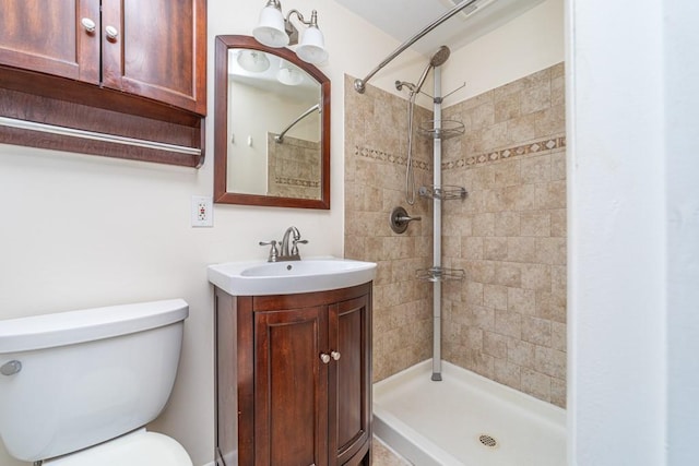 bathroom with a tile shower, vanity, and toilet