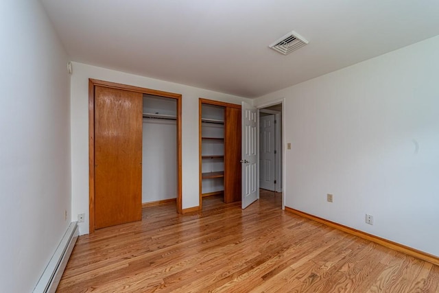 unfurnished bedroom with baseboard heating and light hardwood / wood-style flooring