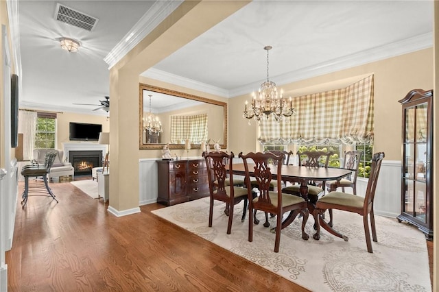 dining area featuring ceiling fan with notable chandelier, wood-type flooring, and ornamental molding