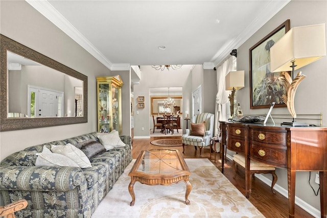 living room with ornamental molding, a notable chandelier, and hardwood / wood-style flooring