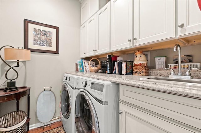 clothes washing area with cabinets, hardwood / wood-style floors, washer and clothes dryer, and sink