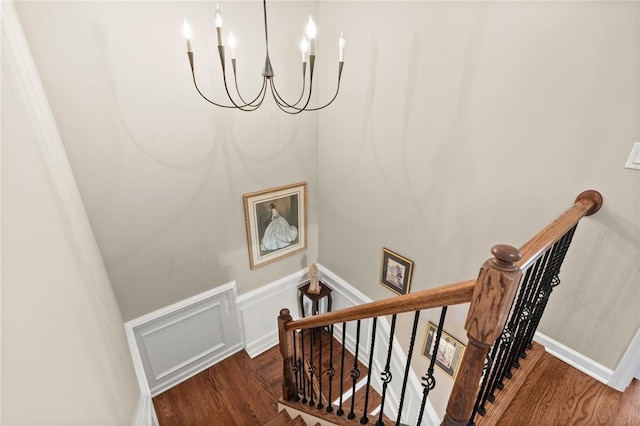 staircase with hardwood / wood-style flooring and a notable chandelier