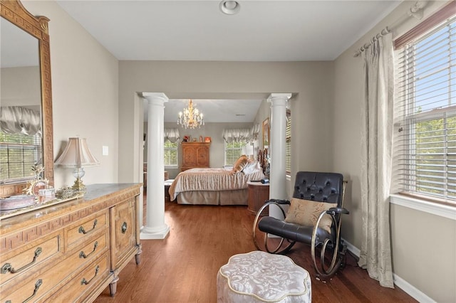 bedroom with dark hardwood / wood-style flooring, ornate columns, and multiple windows